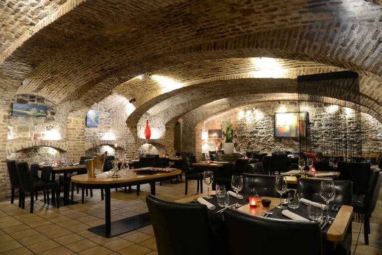 La salle voûtée en pierre des Caves Gourmandes, tables dressées sous les arches
