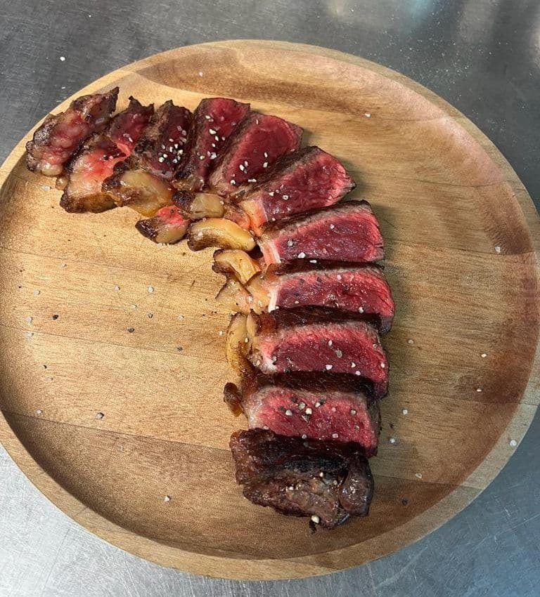 Magret de canard tranché et caramélisé, présenté sur une planche en bois
