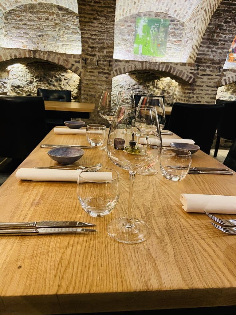 Table dressée pour deux, couverts et verres, dans la cave en pierre